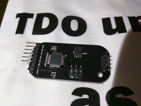 The black SOLDERPEEK circuit board with chips and two sets of pin headers.